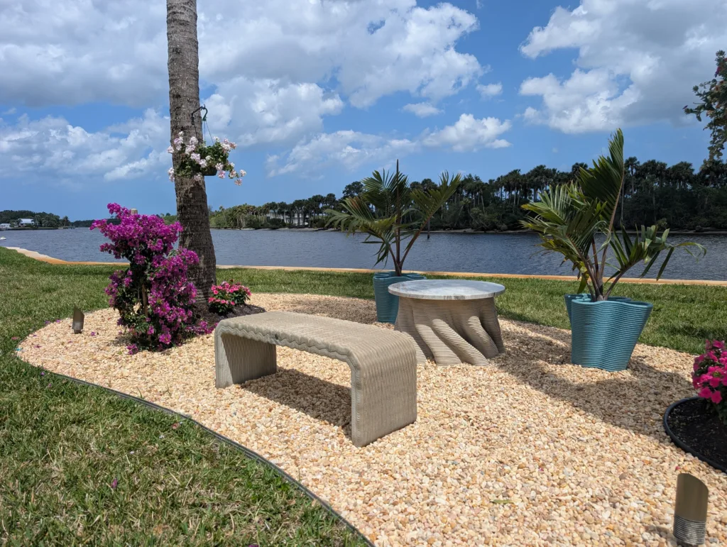 Outdoor seating area featuring 3D concrete printed bench planters and a matching table designed for a modern landscape.